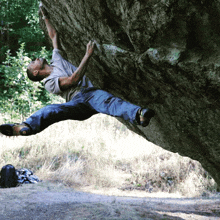 a man is climbing a large rock in a field