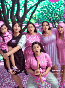 a group of women in pink dresses are posing for a picture with trees in the background