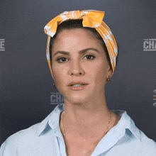 a woman wearing a headband and a blue shirt stands in front of a wall with the word challenge on it