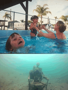 a woman is holding a little girl in a swimming pool next to a skeleton