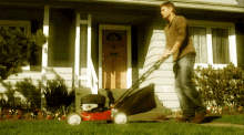 a man is pushing a lawn mower in front of a house that has the letter h on the front door