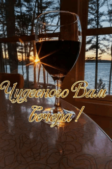 a glass of wine sits on a table in front of a window with the words " чудесно вам вечера " written on it