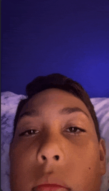 a young boy laying on a bed with a blue wall in the background