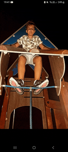 a young boy is sitting on a slide with the time 19:41