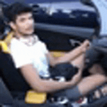 a man is sitting in the driver 's seat of a car holding a cell phone .