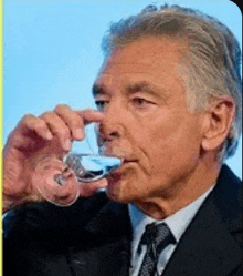 a man in a suit is drinking from a glass