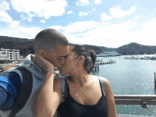 a man and a woman are kissing in front of the water