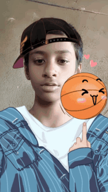 a boy wearing a hat holds a basketball with a face drawn on it