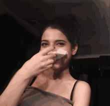 a woman wipes her nose with a napkin while sitting in a car