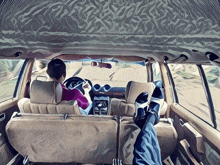 a painting of a man driving a car with his feet on the back seat