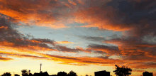 a sunset over a residential area with a telephone pole in the foreground