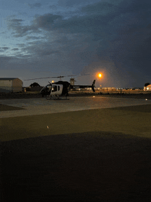 a black and white helicopter with the letters nsb on the side sits on a runway at night