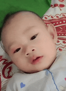 a baby is laying on a bed and looking at the camera with a green background .