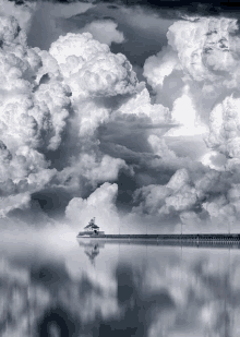 a black and white photo of a lighthouse in the middle of a cloudy sky