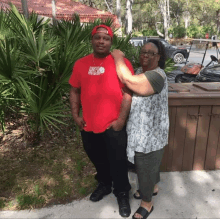 a man wearing a red shirt that says north face stands next to a woman