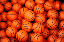 a pile of small orange basketballs with black stripes