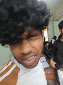 a man with braces on his teeth is wearing a white shirt with brown stripes