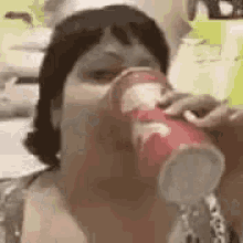 a woman is drinking out of a red cup .