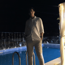 a man stands in front of a swimming pool at night