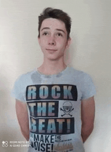 a young man is wearing a t-shirt that says `` rock the beat '' .