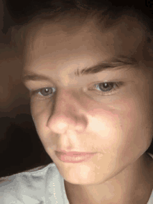 a close up of a young man 's face with a white shirt