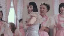 a group of girls are standing in a room wearing pink dresses and dancing .