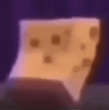 a piece of cheese with holes in it is sitting on a table in front of a purple background .