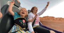 a woman and a little girl are riding a roller coaster and the little girl is wearing a frozen dress