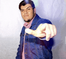 a man in a denim jacket is pointing his finger