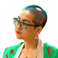 a woman with a shaved head wears glasses and a green shirt with strawberries on it