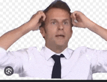 a man in a white shirt and tie is scratching his head with his hands