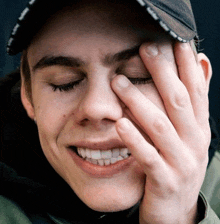 a young man covering his face with his hand and wearing a hat that says ' timberland ' on it