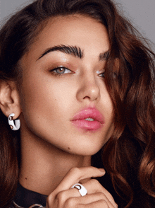 a close up of a woman 's face with earrings and a ring