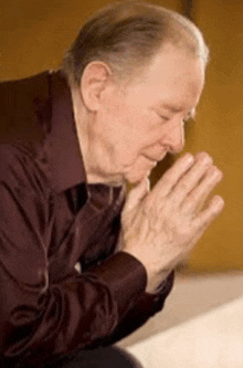 a man is praying with his hands folded in prayer .