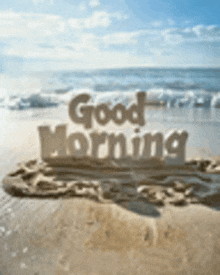 the word good morning is written in the sand on the beach .