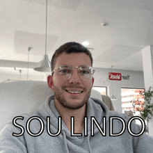 a man wearing glasses and a grey hoodie with the words sou lindo written on the bottom