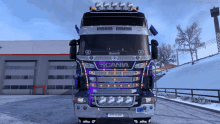 a scania truck is parked in the snow in front of a building