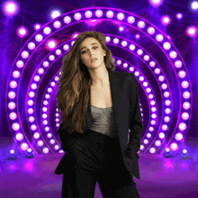 a woman in a black suit is standing in front of a purple light circle