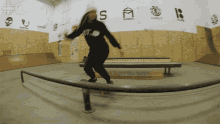 a skateboarder is doing a trick on a railing in a gym with gem written on the wall behind her