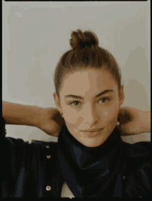 a woman with her hair in a bun has her hands behind her head