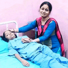 a woman is standing next to a girl in a hospital bed who is wearing a shirt that says ' shiva ' on it