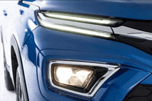 a close up of a blue car with its headlights on