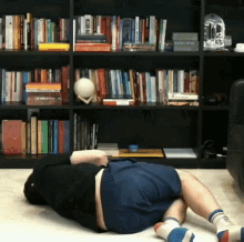 a man is laying on the floor in front of a bookshelf that has a book called " a brief history of the world "