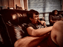 a man sitting on a couch wearing a shirt that says ' i 'm a freak ' on it