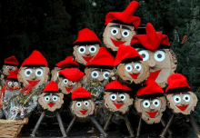 a group of wooden faces wearing red hats with googly eyes