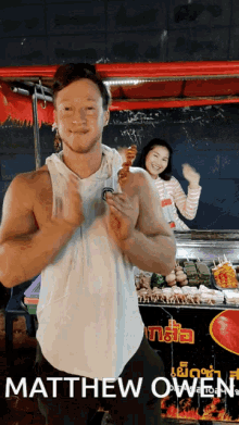 a man in a white tank top holds a skewer in front of a food stand that says matthew owen