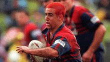 a man with red hair is holding a rugby ball and his jersey says nsw