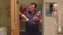 a man holding a trophy in front of a skeleton and a poster that says " understanding the muscular system "