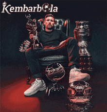 a man is sitting in a chair holding a trophy and the word kembarbola is on the bottom