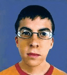 a young man wearing glasses is looking at the camera with a blue background .